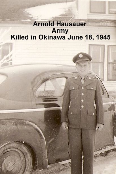 Private First Class Arnold H Hausauer in uniform standing in front of a car photo