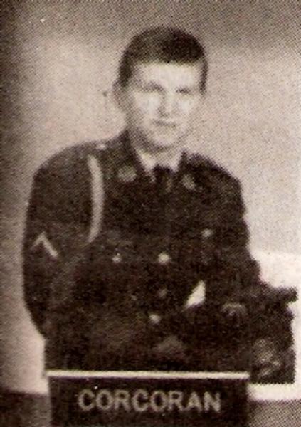 The photograph shows a formal black‑and‑white military portrait of a service member identified by the nameplate “CORCORAN.” 