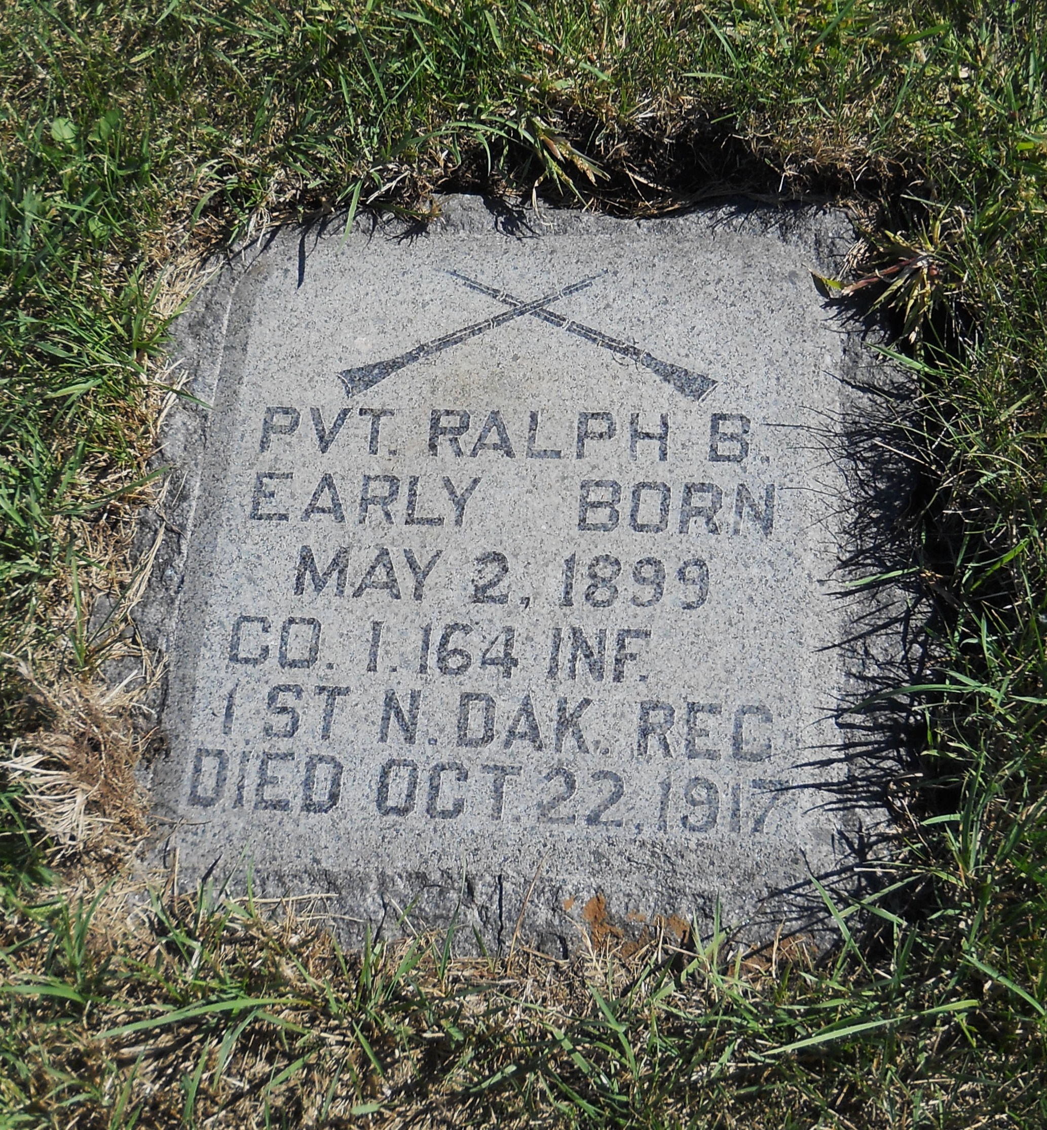 Stone grave marker for Private Ralph B. Early with crossed rifles and military service details.