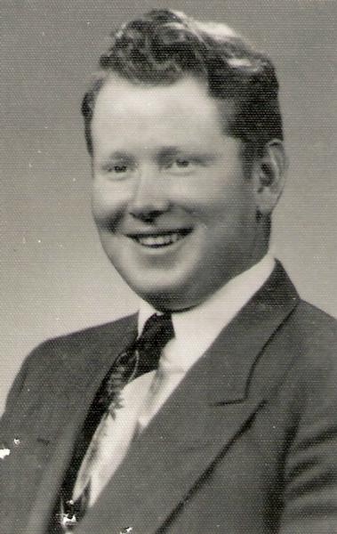 This is a classic mid‑20th‑century studio portrait of a man dressed in formal civilian clothing. The photograph is black‑and‑white and printed in a smooth, high‑quality style typical of professional portrait studios of the 1950s–1970s.