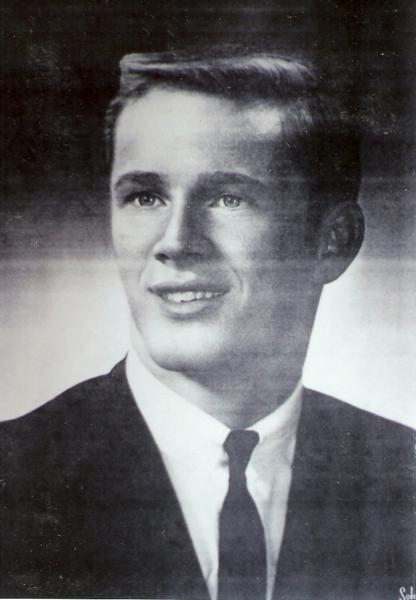 This portrait shows a young person dressed in formal civilian clothing, photographed in a classic mid‑20th‑century studio style. 