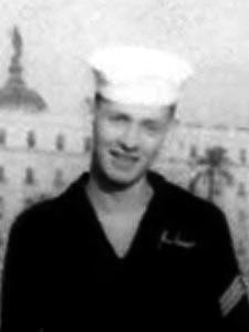 This photograph shows a U.S. Navy sailor in uniform, captured outdoors in what appears to be a warm or coastal location.