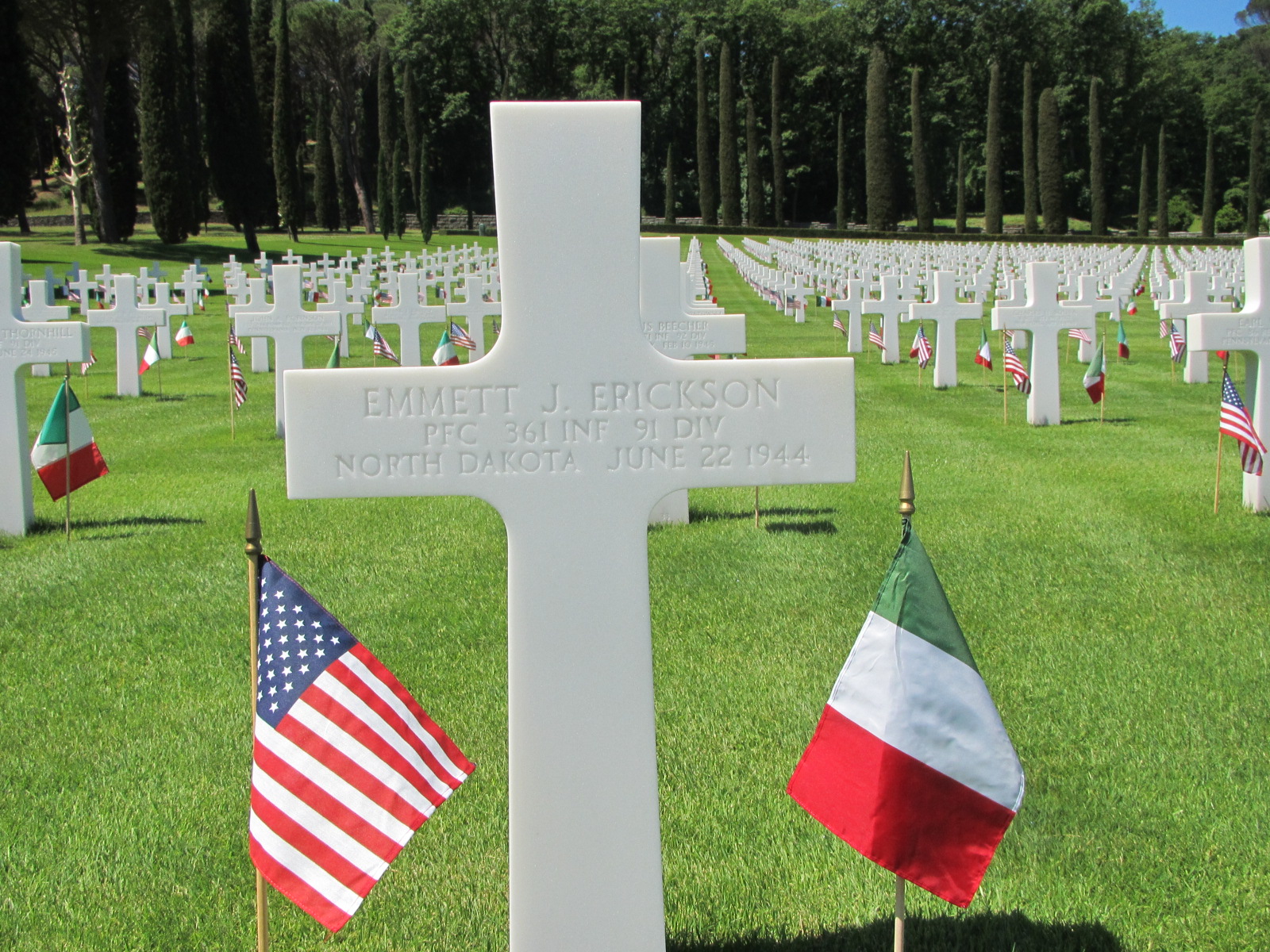Private First Class Emmett J Erickson cross grave marker with small flags photo