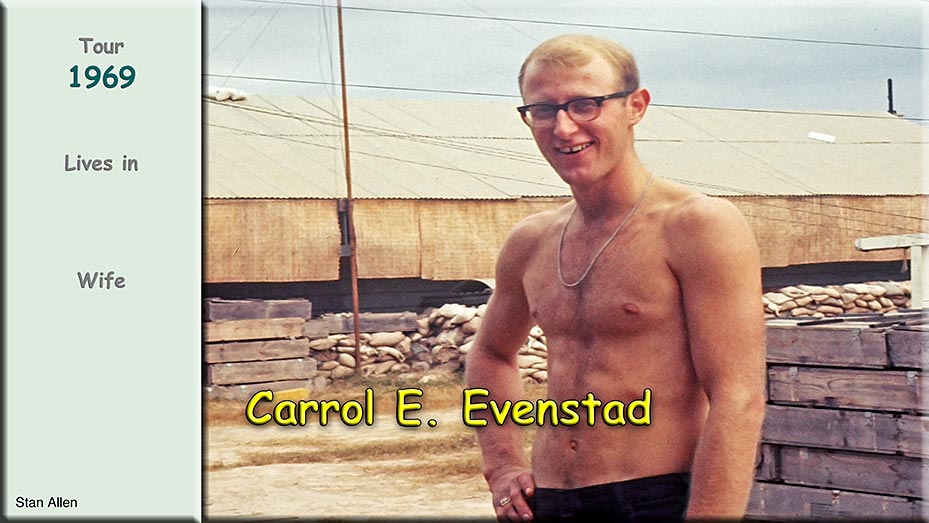 Photo of Carrol Evenstad. The photo shows him standing outdoors in what appears to be a military encampment or base. He’s wearing glasses and his posture is relaxed—hands resting at his sides. 