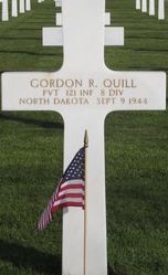 Private Gordon R Quill cross grave marker with small American flag photo