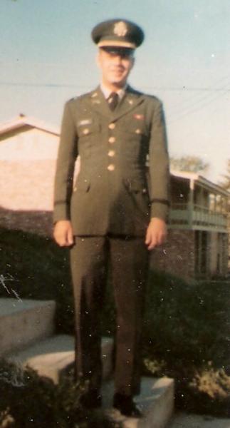 Rodger Hertel photo shows a service member standing outdoors on a small concrete step, dressed in a formal military dress uniform.