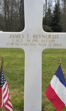 Staff Sergeant James T Reynolds cross grave marker with small flags photo