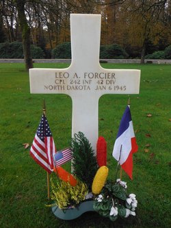 Corporal Leo A Forcier cross grave marker with small flags and flowers photo