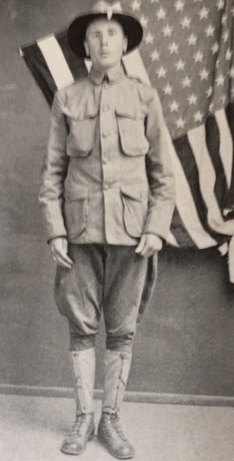 A black-and-white historical photograph of Howard McLean in a U.S. Army doughboy uniform, featuring a campaign hat, tunic with four pockets, and puttees, standing before a large American flag.