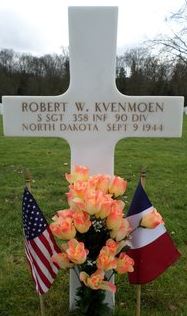 Staff Sergeant Robert W Kvenmoen cross grave marker with flowers and small flags photo