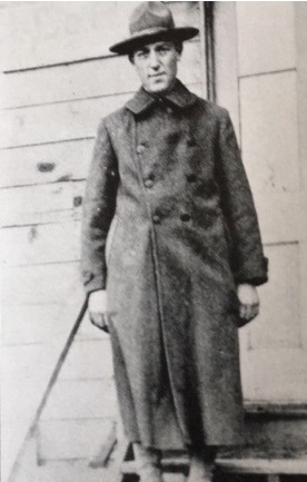 Vintage black-and-white portrait of Valentine Schneider a World War I-era soldier wearing a full-length overcoat and campaign hat.