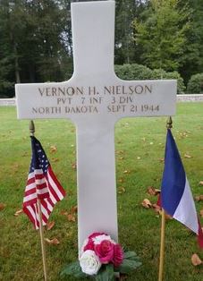 Private Vernon H Nielson cross grave marker with small flags and flowers photo
