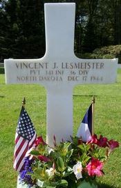 Private Vincent J Lesmeister cross grave marker with small flags and flowers photo