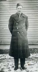 Technician Fourth Class William J McCann in uniform standing with coat photo