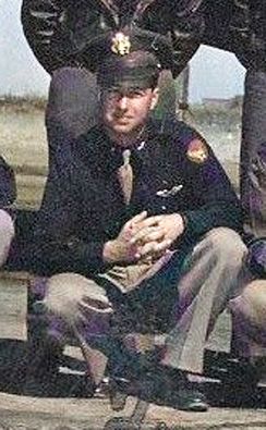 Second Lieutenant Douglad A McLean in uniform squatting in front of airplane photo