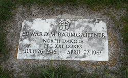 This image shows a white military gravestone set flat into the ground, surrounded by short green grass.