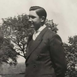 Second Lieutenant George L Murray in civilian clothes standing outside in front of trees photo