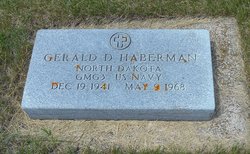 The photograph shows a gray upright military gravestone for Gerald Haberman set in a grassy cemetery.