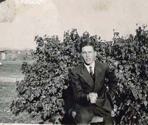 Corporal Leo W Manske in suite and tie sitting down outside photo