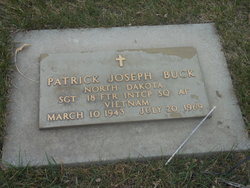 This is a bronze military grave marker honoring Patrick Joseph Buck, set into a concrete frame and surrounded by grass.
