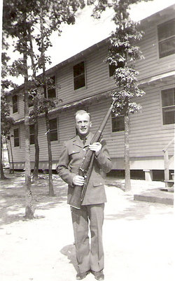 Private First Class Vernon E Westberg in uniform standing outside holding rifle photo